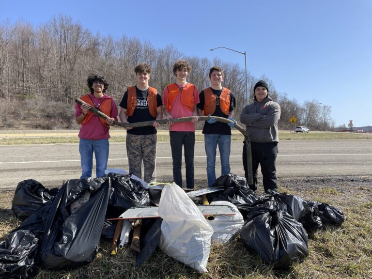 a group of students standing in front of garbage bags