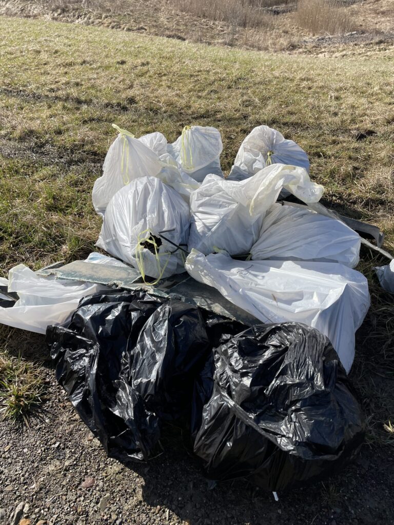 a pile of plastic trash bags in the grass