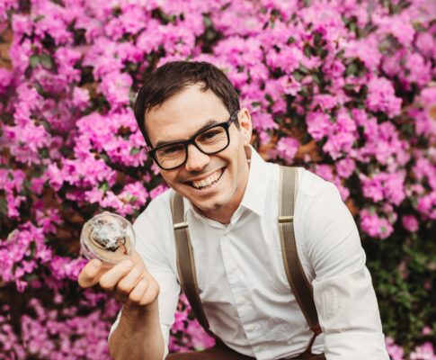 a person in glasses holding a glass ball