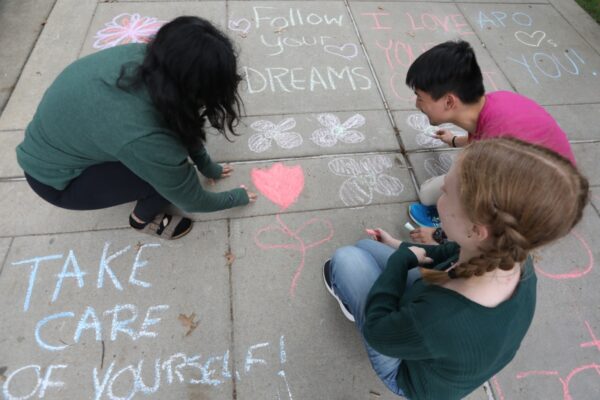 students writing mental health messages in chalk