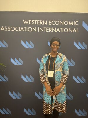 Professor smiling in front of sign