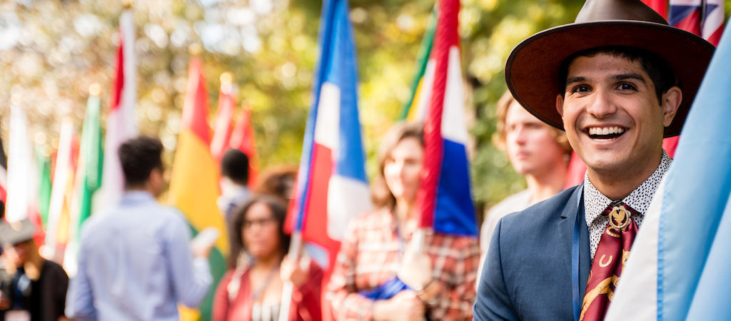 a student holding a microphone in front of a group of people holding flags