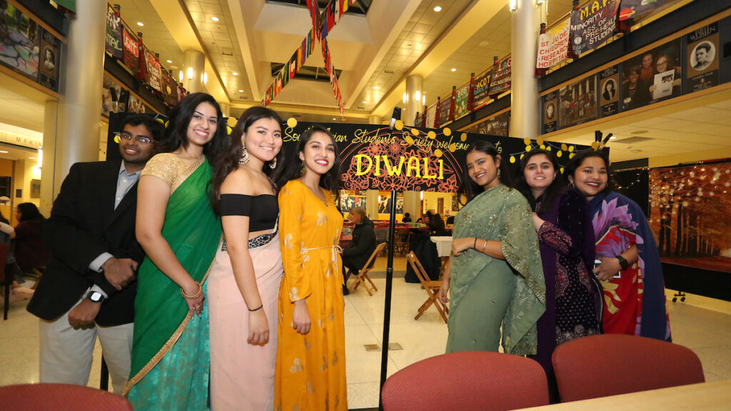 a group of women in dresses with a sign that reads Diwali in the background