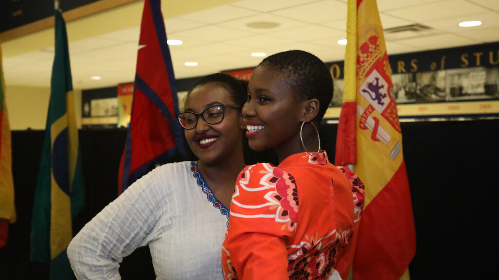 two women standing together between two flags