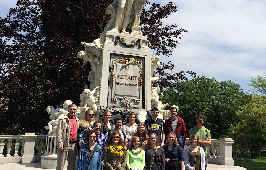 a group of students posing for a photo in front of a statue