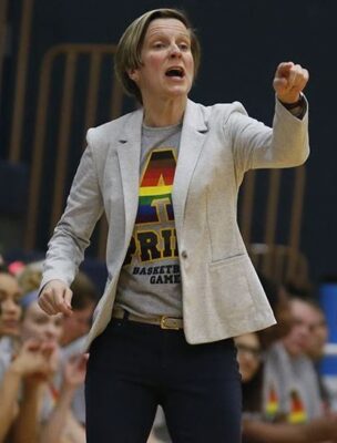 a person in a grey blazer talking in front of a crowd