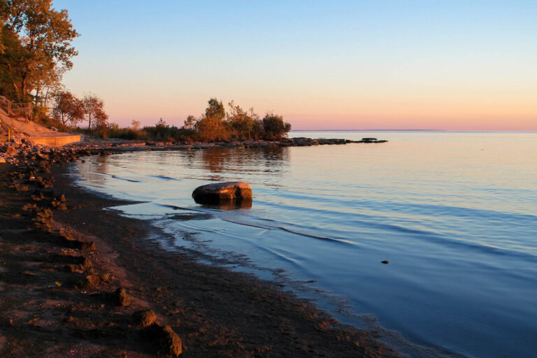 a rock in the water at sunset