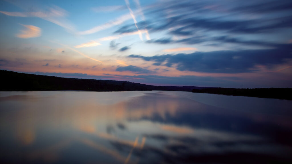 a body of water with a blue sky and clouds