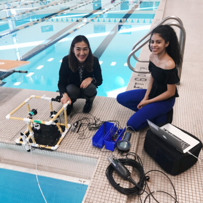 two women with scientific equipment next to a swimming pool