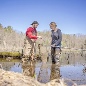 two students standing in water with a net