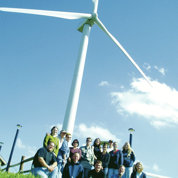 Group of students seated at the base of a wind turbine.